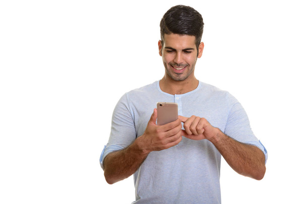 jong gelukkig Perzische man glimlachen tijdens het gebruik van mobiele telefoon - Foto, afbeelding