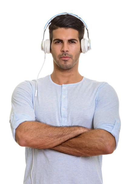 Young handsome Persian man listening to music with arms crossed - Foto, Imagem