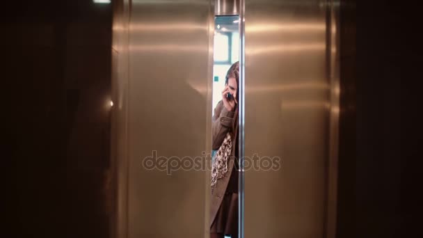 Asansör kapı açıktır. Asansör ayakta ve smarphone üzerinde konuşmak ve gidiyor kadın. - Video, Çekim