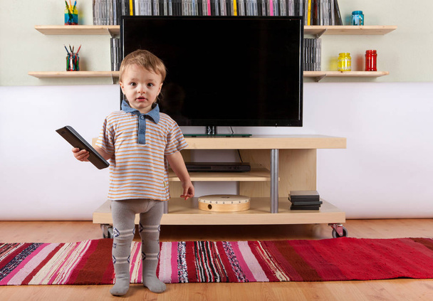 Cute baby boy with remote control in front of the TV - Foto, Imagem