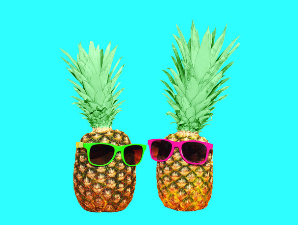 Two pineapple and sunglasses on blue background, colorful ananas - Foto, Bild