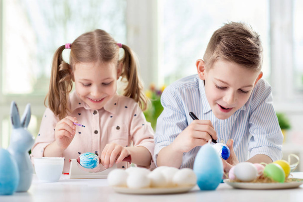 Two happy children having fun during painting eggs for easter in - Photo, image
