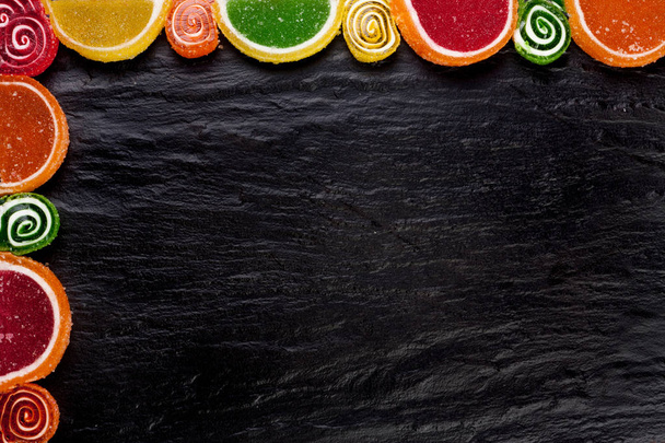 Frame from fruit jellies on a dark background. Top view with copy space - Фото, изображение