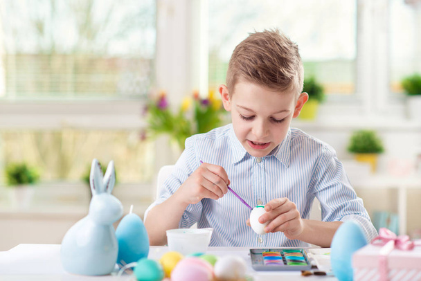 Happy child boy having fun during painting eggs for easter in sp - Фото, изображение