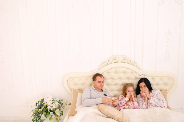 Fiatal család kapott beteg vagy beteg tüsszentés az ágyban otthon - Fotó, kép