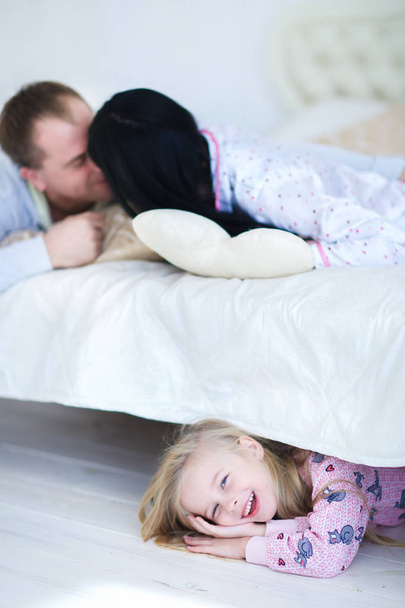 Daughter hiding under bed, Mom and Dad spoken at home - 写真・画像
