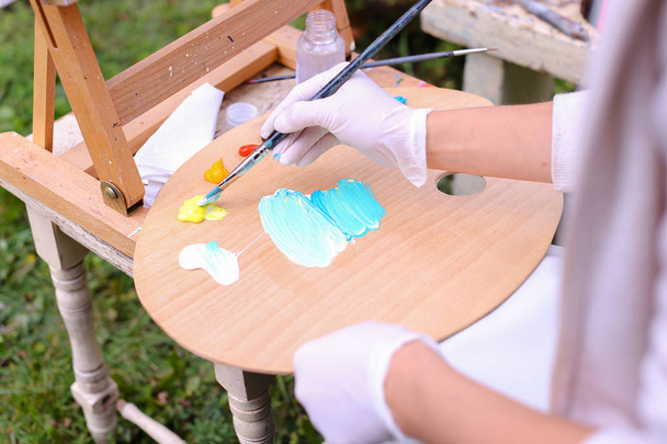Naiset taiteilijat käsin puristetaan putkista öljyvärimaalaus puinen vaalea
 - Valokuva, kuva