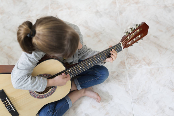 9-letnia dziewczyna, Nauka gry na gitarze.  - Zdjęcie, obraz
