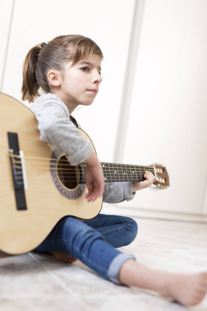 9-letnia dziewczyna, Nauka gry na gitarze.  - Zdjęcie, obraz