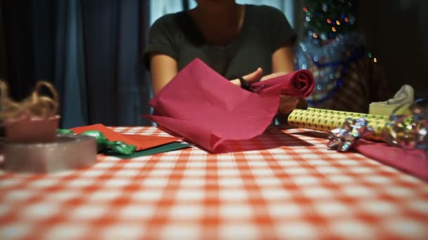 Female cutting pink wrapping paper for packing presents - Footage, Video