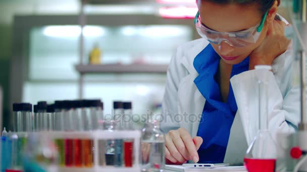 Studentka chemii patrząc na mobile. Kobiety Chemika przewijanie na telefon - Materiał filmowy, wideo
