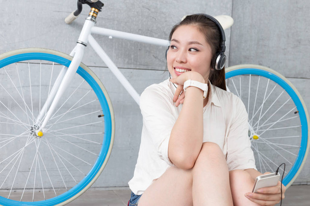 chinese woman listening music with bike - Photo, Image