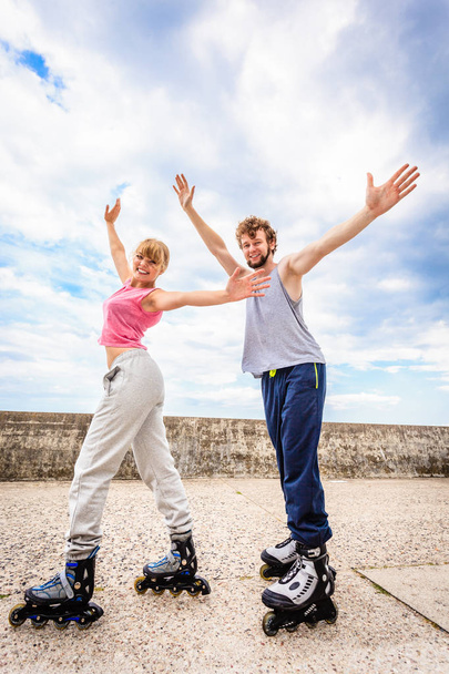 Two people on rollerblades with spread arms. - Fotoğraf, Görsel