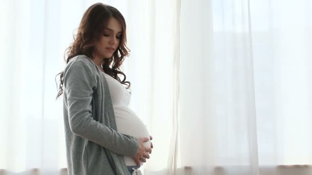 Kobieta w ciąży dotykając brzuch z zamkniętymi oczami - Materiał filmowy, wideo