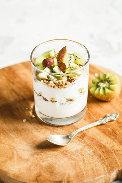 glass of yogurt with granola and kiwi slices. breakfast concept - Фото, изображение