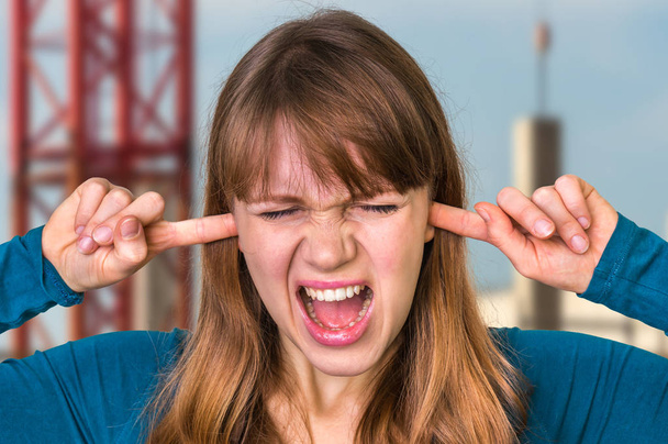 Femme couvrant ses oreilles pour se protéger du bruit fort
 - Photo, image