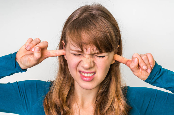 Kobieta zamyka uszy palcami, aby chronić przed głośny hałas - Zdjęcie, obraz