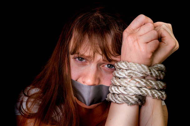 Tied rope hands of abused woman isolated on black - Photo, Image