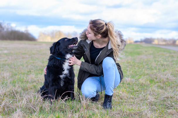Loving young woman with her loyal black dog - Photo, Image