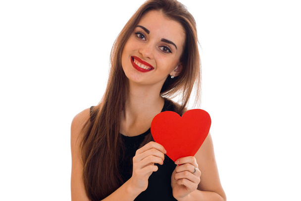 happy young brunette woman with red lips and heart in her hands posing isolated on white background - Foto, afbeelding