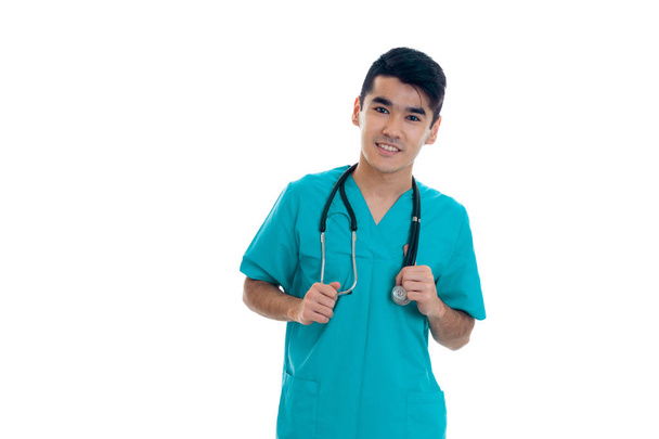 portrait of cheerful young brunette male doctor in uniform with stethoscope posing isolated on white background - Zdjęcie, obraz