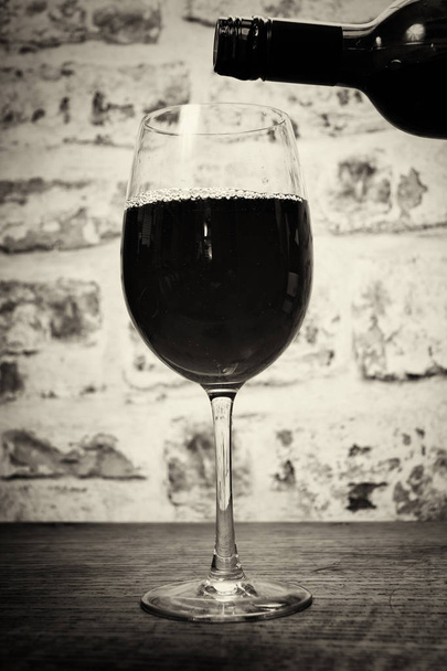 Volledige bodied rode wijn wordt gegoten glas - Foto, afbeelding