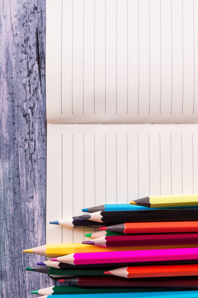 Цветные карандаши рядом с запиской на деревянном фоне. Вид сверху. Копирование пространства
. - Фото, изображение