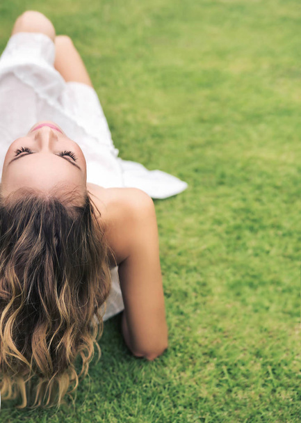 新鮮な芝生で休んで若い女性 - 写真・画像