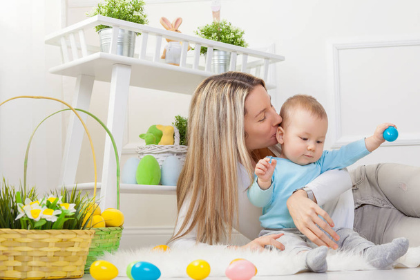 Delighted mother and her child enjoying the Easter egg hunt at home - Foto, imagen