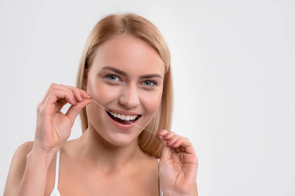 Pretty woman flossing her oral cavity - Foto, immagini