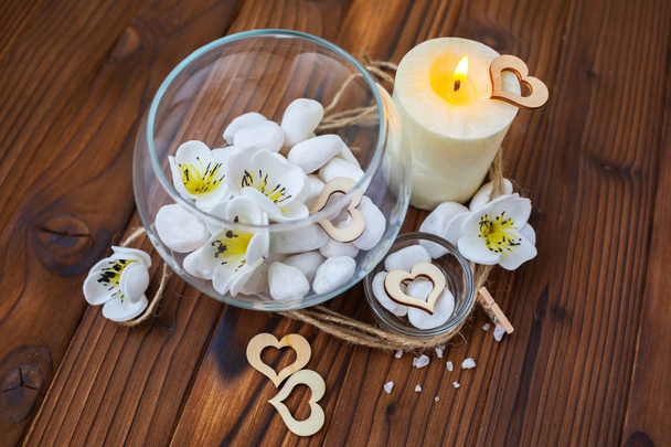 Білі камені в скляній вазі, квіти і велика свічка для спа та відпочинку
 - Фото, зображення