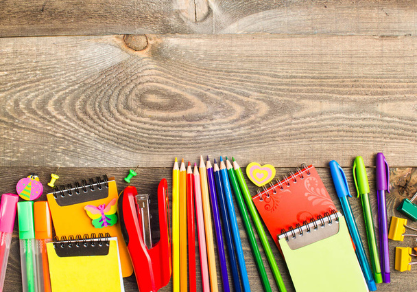 Iskola írószer termékek, mint a gemkapocs, csapok, jegyzetfüzet, toll, ceruza, vonalzó, olló, fából készült asztal feküdt a hely írni a szöveget - Fotó, kép