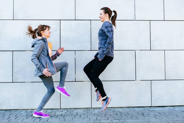 Kaksi urheilullinen naiset kasvotusten käyttäessään maraton ja harjoitus kunto
. - Valokuva, kuva