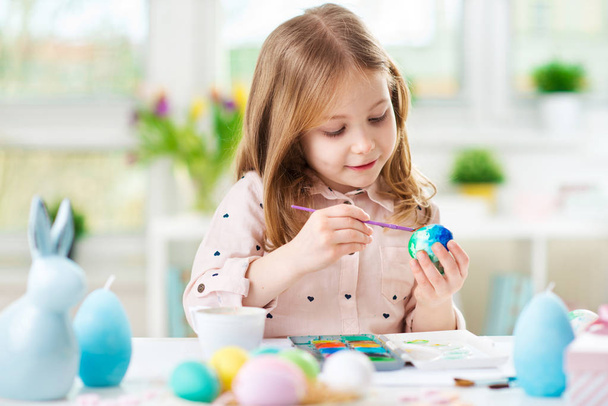 Happy pretty child girl having fun during painting eggs for Easter in spring - Foto, Bild