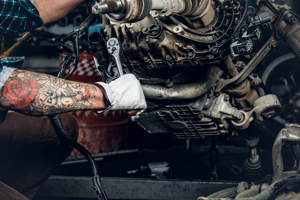 Человек с татуировкой на ручном ремонте двигателя
 - Фото, изображение