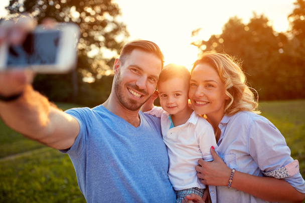 Man and woman with young son taking selfie photo - Foto, imagen