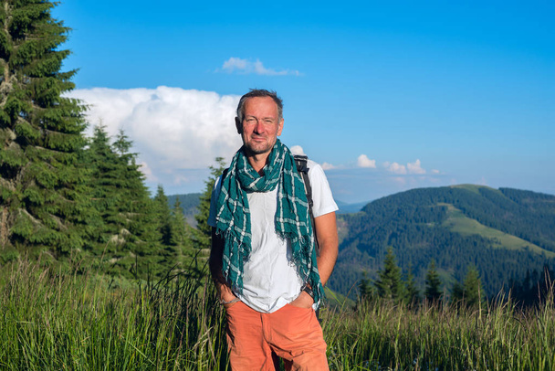 Smiling man traveler is standing on the alpine meadow  - Фото, зображення