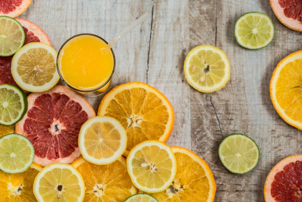 szklanki soku pomarańczowego na tle drewna z kawałkami owoców cytrusowych - Zdjęcie, obraz