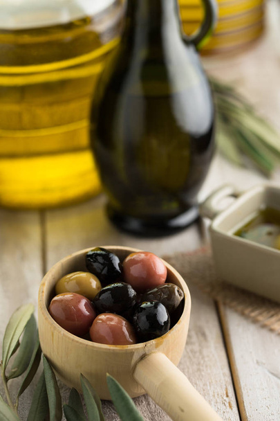 Zeytin, zeytinyağı şişesi ve zeytinyağı yaprakları kadar yakın. - Fotoğraf, Görsel