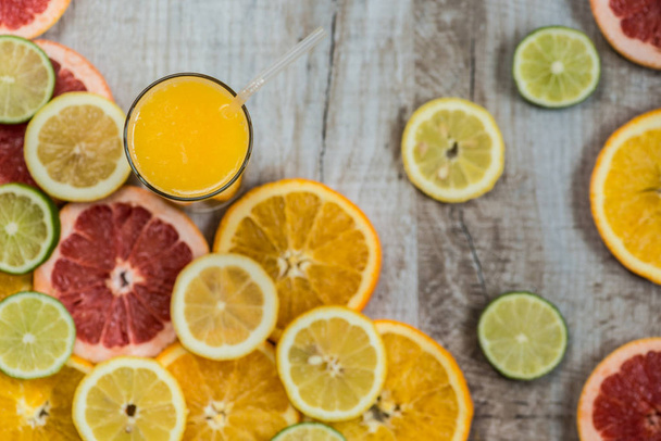 szklanki soku pomarańczowego na tle drewna z kawałkami owoców cytrusowych - Zdjęcie, obraz