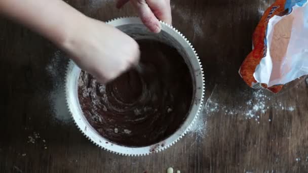 Vista superior revolviendo masa de galletas de chocolate con una cuchara en un tazón de plástico blanco
 - Metraje, vídeo