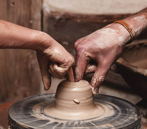 Primer plano de las manos que trabajan en el volante de cerámica
 - Foto, Imagen