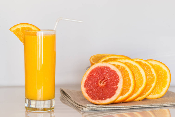 склянка апельсинового соку на білому тлі зі скибочками цитрусових
 - Фото, зображення