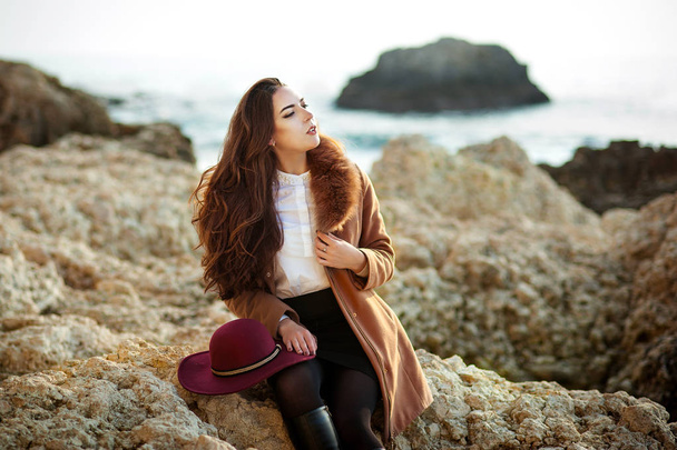 glamourous portrait of the young beautiful woman in a hat and coat of a beach - Foto, immagini