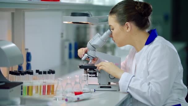 Scientist with microscope in lab. Woman scientist doing microscope research - Felvétel, videó