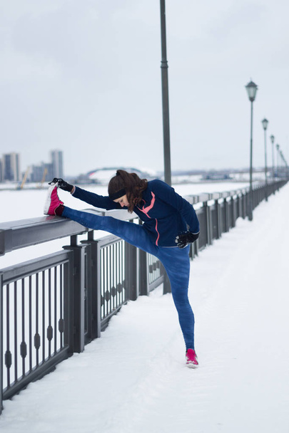 Γυμναστήριο κορίτσι με ροζ αθλητικά παπούτσια που κάνει το τέντωμα έξω στο χειμώνα χιόνι εξωτερική - Φωτογραφία, εικόνα