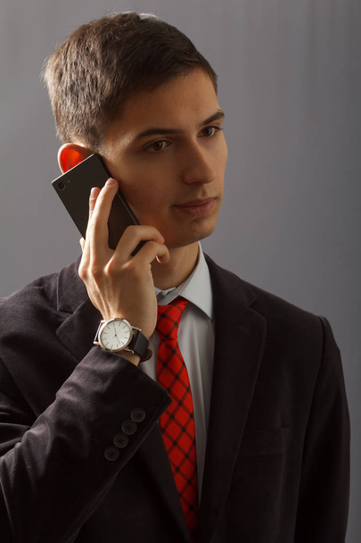 Portrait of young man in suit is speaking on the sell phone - Foto, Bild