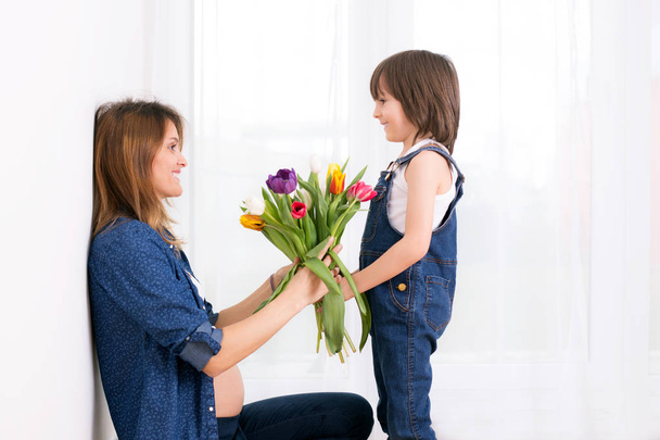 Raskaana oleva äiti, halaa lastaan, vastaanottaa tulppaanit, kukat fo
 - Valokuva, kuva