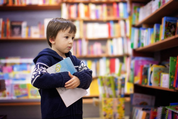 Adorable little boy, sitting in a book store - Фото, изображение