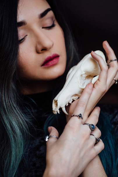 Portrait of a young girl holding a mysterious skull in the hands of a fox. Painted long hair. - Фото, изображение